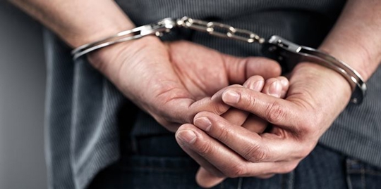 Image of hands bound by handcuffs